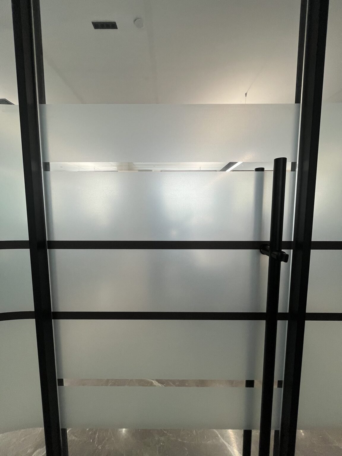 Frosted film banding detail on framed glass partition