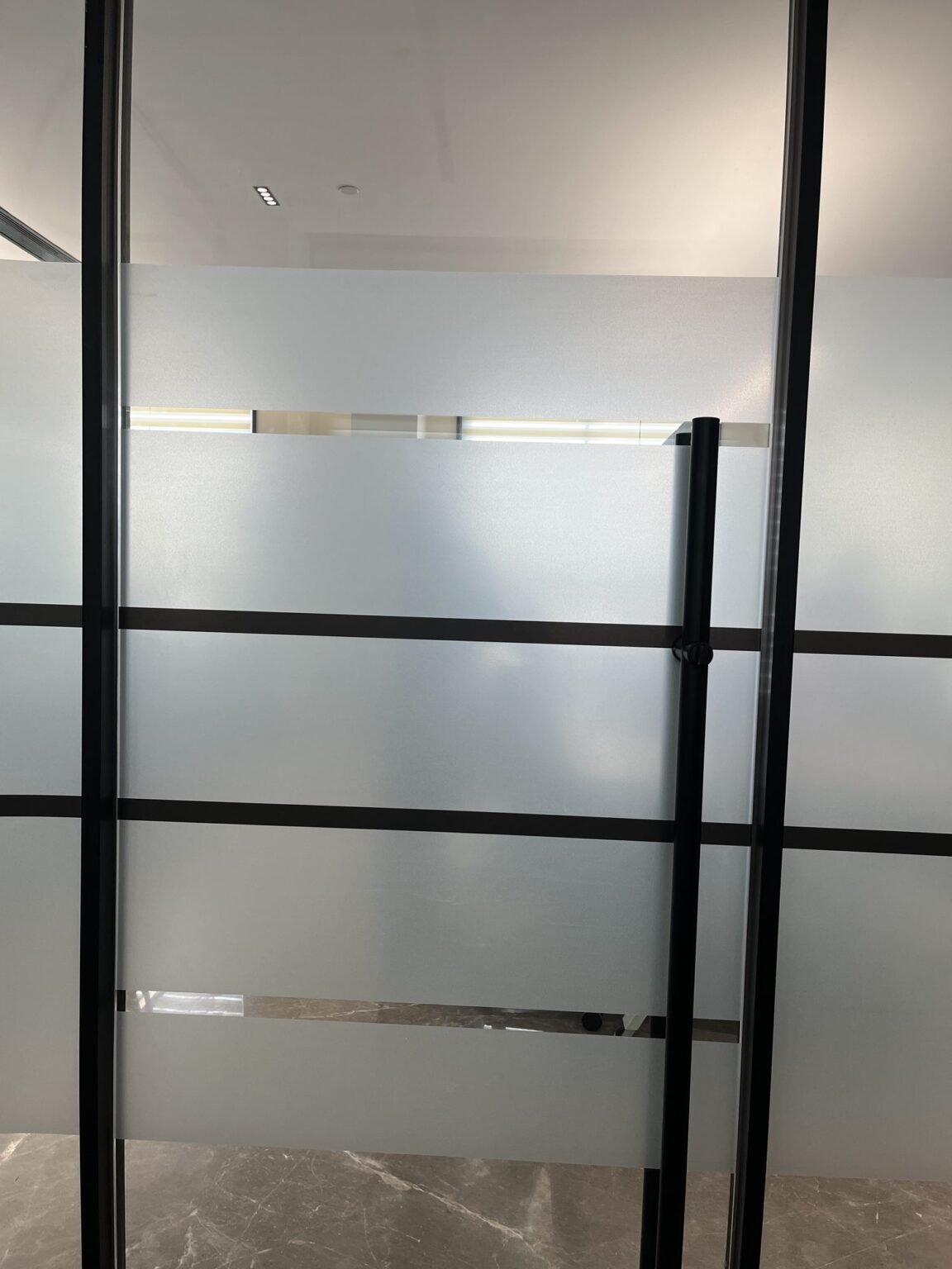 Frosted film banding detail on framed glass partition