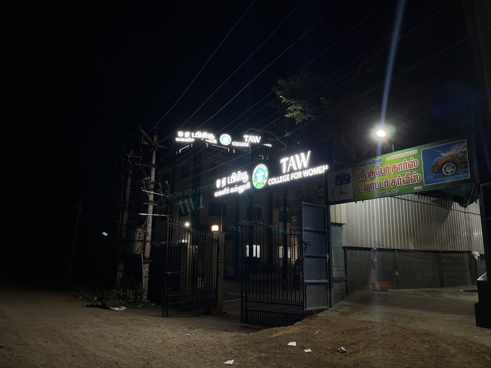 TAW College gate signage lit at night